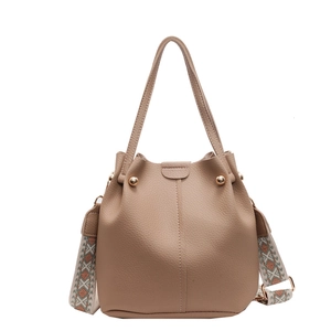 Light brown faux leather bucket bag with gold studs and patterned wide shoulder strap