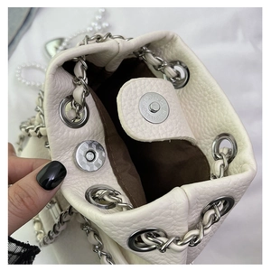 Detail view of white lychee leather bucket bag with magnetic closure and silver chain strap