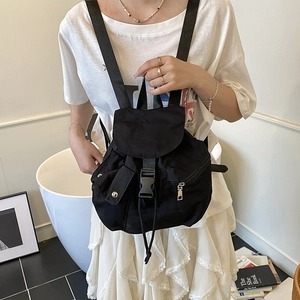 Minimalist black nylon mini backpack with buckle flap shown in casual lifestyle setting
