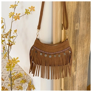 Détail d'un sac bandoulière en daim marron avec franges ethniques et disques métalliques