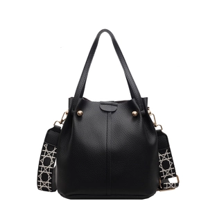 Minimalist black pebble leather bucket bag with wide geometric woven shoulder strap