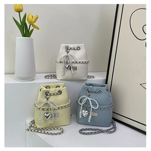 Detailed shot of mini bucket bags with pearl bows and silver chain straps in soft colors