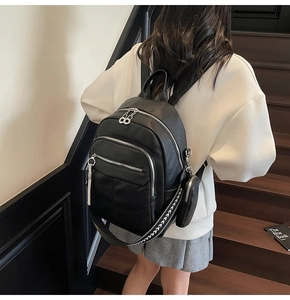 Detailed view of black pebbled leather backpack with silver zippers and patterned straps