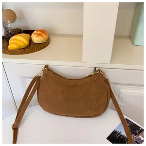 Détail du sac demi-lune en daim marron avec fermeture éclair dorée et décor rustique