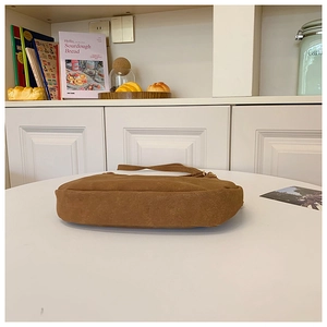 Détail latéral du sac à bandoulière en daim caramel avec finitions dorées et bords arrondis