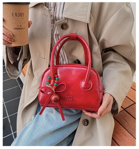 Detail of red patent leather handbag with glossy finish and festive bow charm accessory