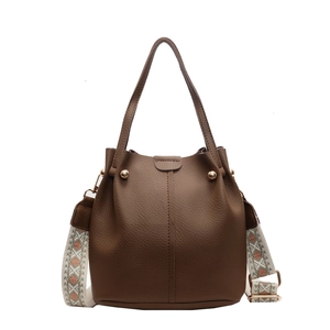Detail of dark brown lychee leather bucket bag with a retro geometric pattern wide strap