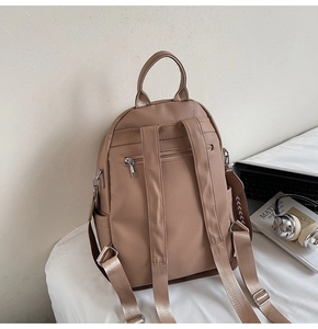 Detailed back view of khaki faux leather backpack with adjustable straps and hidden pocket