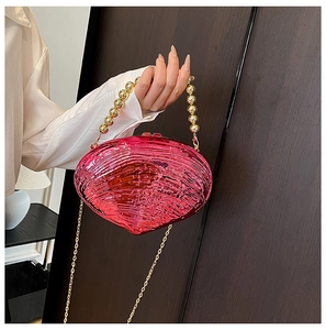 Detail of pink pearlescent shell clutch with gold bead handle and metallic chain strap