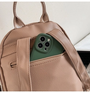 Close-up of the anti-theft back pocket with golden zipper on a light brown leather backpack
