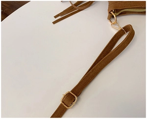 Détail de la boucle réglable et de la fermeture éclair dorée sur sac en daim marron