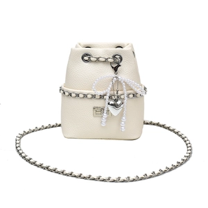Close-up of litchi grain bucket bag featuring pearl bow charm and chain strap