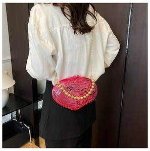 Close-up of hot pink shell-shaped evening clutch with gold bead handle and chain strap