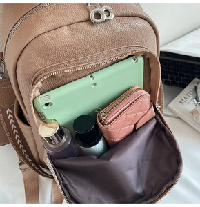 Detailed view of open brown lychee leather backpack showing spacious storage for daily items