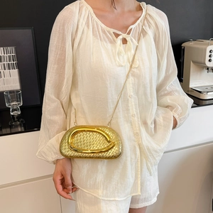 Detail view of a luxury gold woven dinner bag with metal handle and chain strap for women