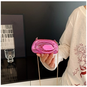 Macro view of metallic rose pink mini bag with gold chain and high-gloss finish