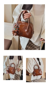 Close-up of brown leather pillow bag featuring vintage beads, bow charm, and metal zipper
