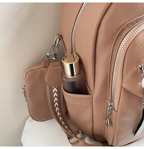 Detail of brown litchi leather backpack side pocket and mini zipper pouch attachment