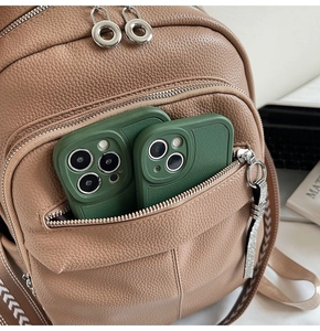 Detail of khaki pebbled leather backpack showing front pocket storage and silver hardware