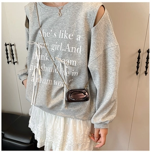 Close-up of a grey shoulder cutout sweatshirt with white ribbon ties and metallic mini bag