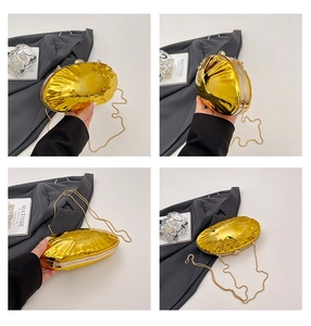 Detail of golden shell evening bag showing electroplated wave texture and fine chain strap