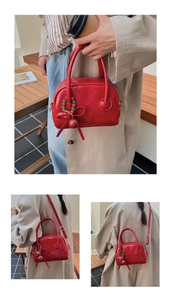 Close-up of red leather handbag with festive bead charms and adjustable shoulder strap