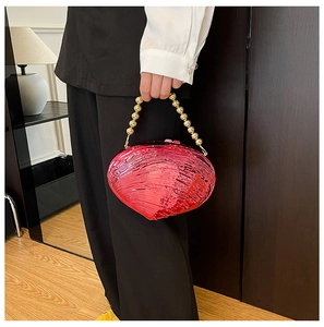 Detail of pink shell-shaped acrylic clutch bag with golden beaded handle accessory