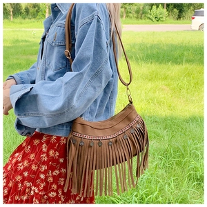 Détail extérieur d'un sac bandoulière marron à franges avec broderies ethniques