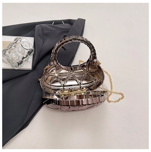 Dettaglio della pochette geometrica in acrilico argento con manico ad anello e catena oro