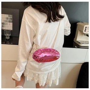 Detail of metallic pink shell bag with golden chain strap on model in indoor setting