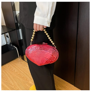 Macro detail of fuchsia shell clutch bag featuring golden bead handle and rippled texture