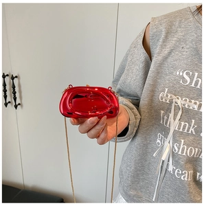 Detail of red metallic hard shell evening clutch with gold chain and glossy mirror finish