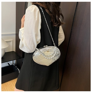 Detailed view of silver shell-shaped evening bag with pearl handle and metal chain