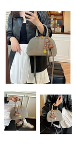 Chic gray shell-shaped handbag detail with heart pendant and yellow smile charm accents