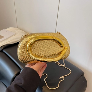 Detailed view of the gold woven evening bag with a wide polished metal handle and chain strap