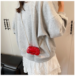 Detailed shot of a red mini acrylic crossbody bag with a fine gold chain strap