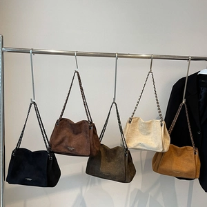 Five suede shoulder bags with chain straps in black, brown, green, cream, and tan colors