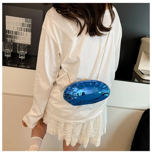 Detail of royal blue mirrored shell clutch with gold chain strap on a white outfit