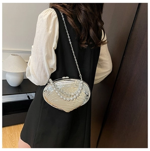 Detail of silver shell-shaped evening bag with pearl handle and metal chain strap