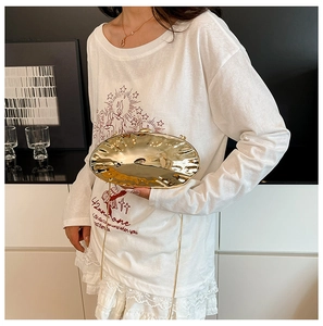 Detail of a wavy gold marble texture shell evening clutch with a sleek metal chain strap