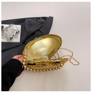 Macro detail of golden shell evening bag featuring pearl beaded handle and metallic chain
