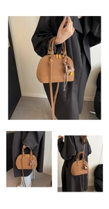 Macro detail of brown shell bag with golden hardware and mini envelope charm accessory