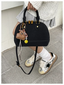 Detail of black shell-shaped handbag with acrylic chain and heart charms on a model
