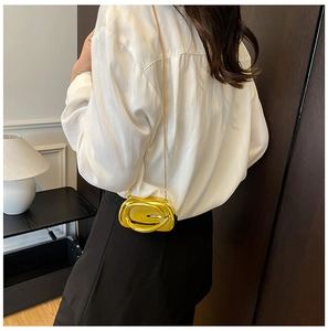 Glossy gold oval evening bag with chain strap shown on model's shoulder