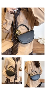 Detail view of black crescent saddle bag with gold metal ring and leather top handle