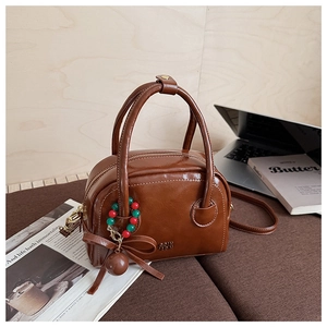 Detail of vintage brown PU leather handbag with COIN CON lettering and cute bow charm