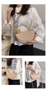 Detail of beige saddle bag with large gold metal ring handle and crossbody strap