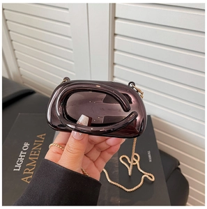Detail of a mini bronze metallic evening bag with high-gloss finish and gold chain strap