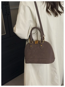 Detail of dark brown shell handbag with gold hardware and removable shoulder strap
