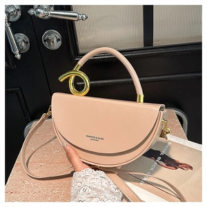 Detail of light apricot saddle bag with a golden spiral handle and leather texture